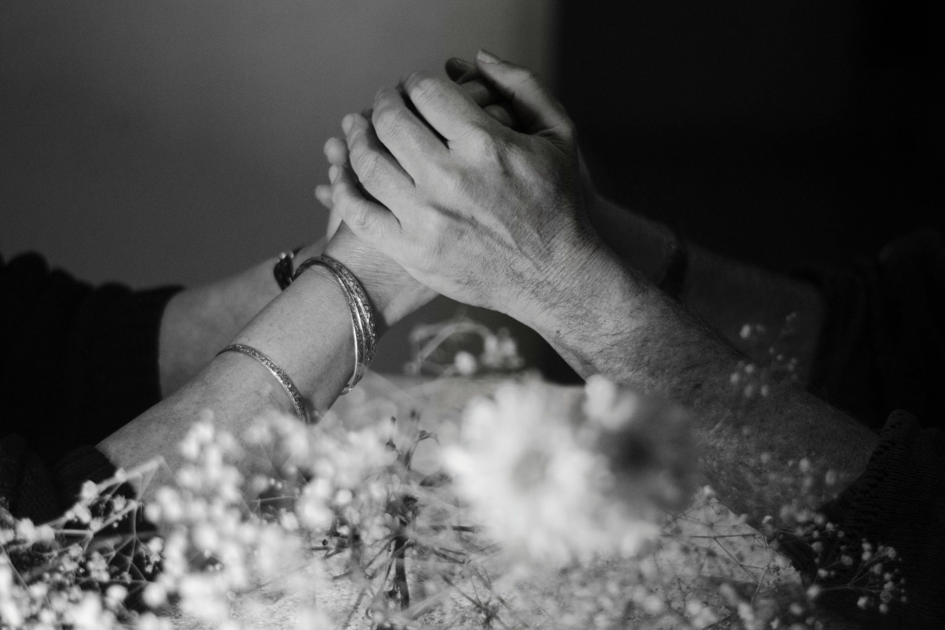 A harmonious monochrome image of intertwined hands surrounded by delicate flowers, symbolizing love and connection.